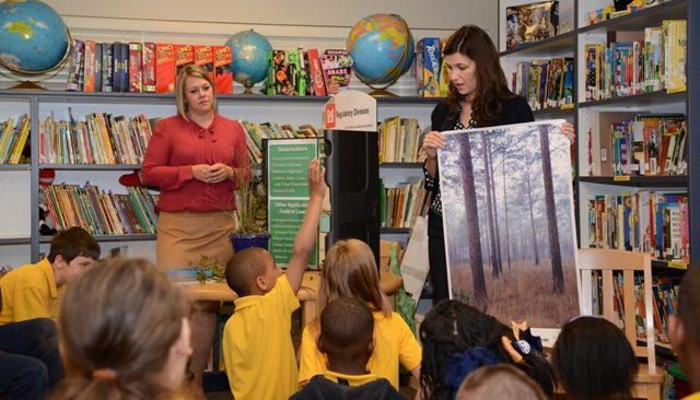 Sandy Gibson looks on as Sheri Zettle, regulatory division display a poster of wetlands.